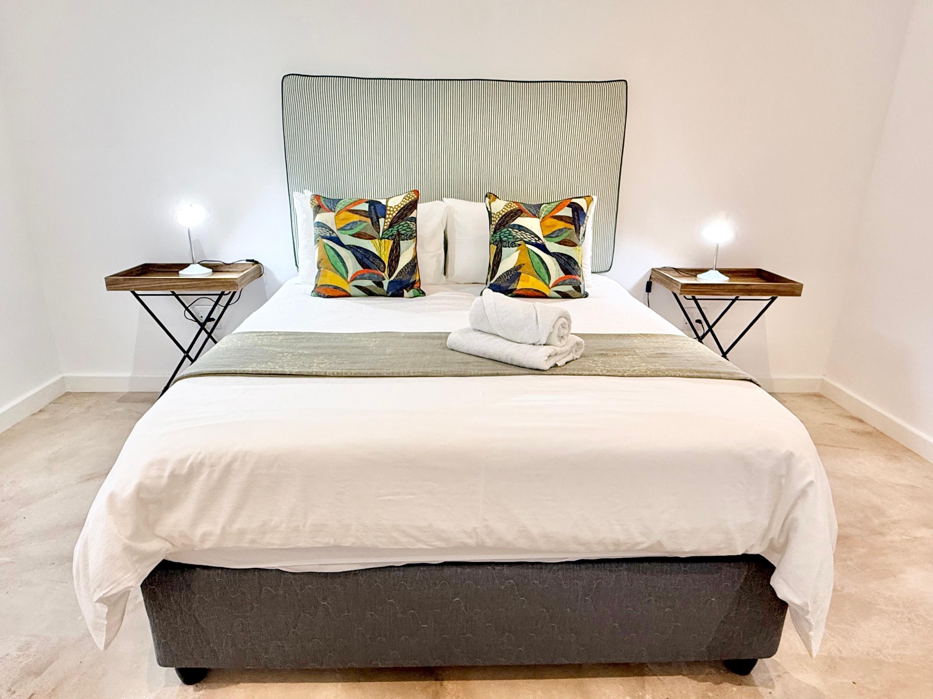 Main bedroom with upholstered headboard and bright linen